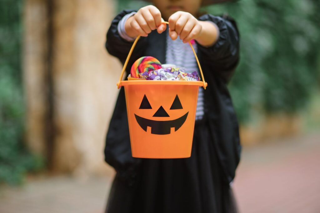 A child holding a trick or treat bucket full of candy.